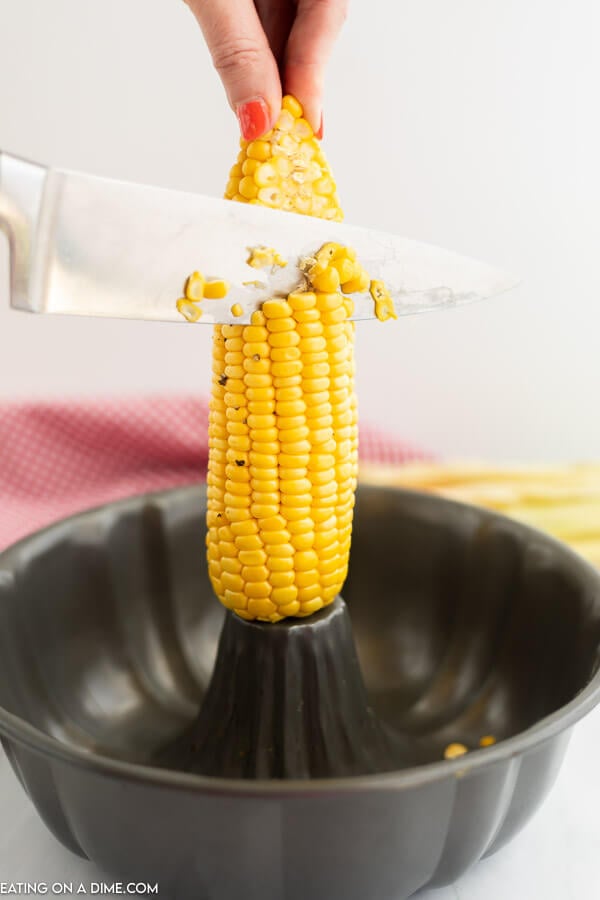 Close up image of kernels being cut off the cob into a bundt pan. 