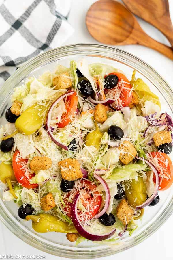 Olive Garden Salad in a bowl with wooden tongs. 