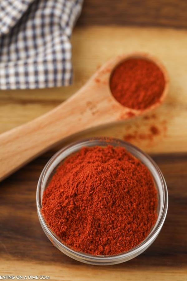 close up image of paprika powder in a jar with a teaspoon of paprika in the background. 