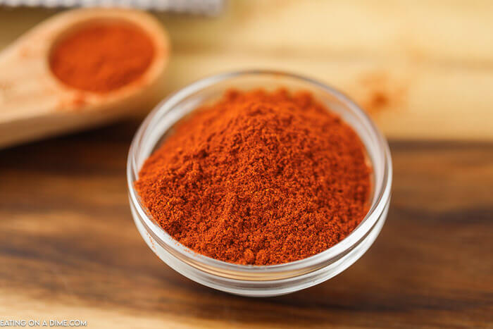 close up image of paprika powder in a jar with a teaspoon of paprika in the background. 