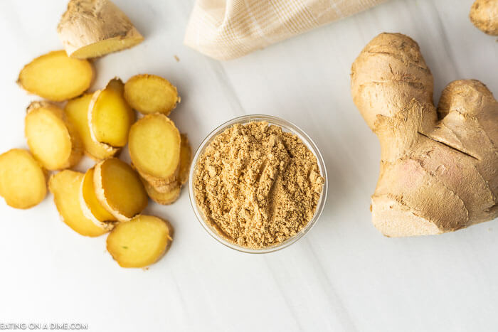 Close image of a ginger root, slice ginger and a bowl of ground ginger. 