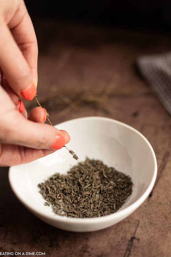 Removing dried thyme from the stem and placing in a bowl.