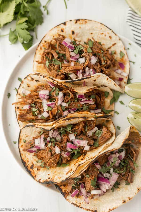 Beef Barbacoa Tacos on a place with a side of limes. 