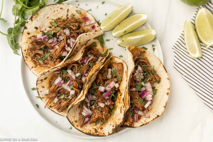 Instant Pot Barbacoa Beef Recipe can be ready with very little effort for a flavorful meal your family will love. Enjoy tender beef seasoned to perfection. Beef Barbacoa Tacos on a place with a side of limes.