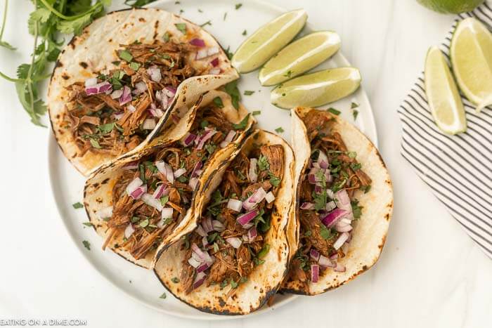 Beef Barbacoa Tacos on a place with a side of limes. 