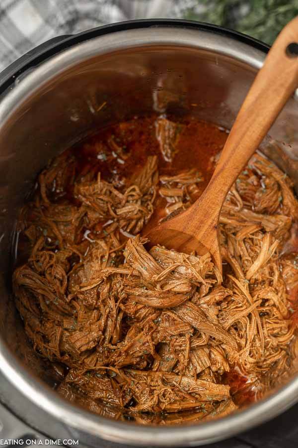 Close up image of BBQ Brisket in the Instant Pot with a wooden spoon. 