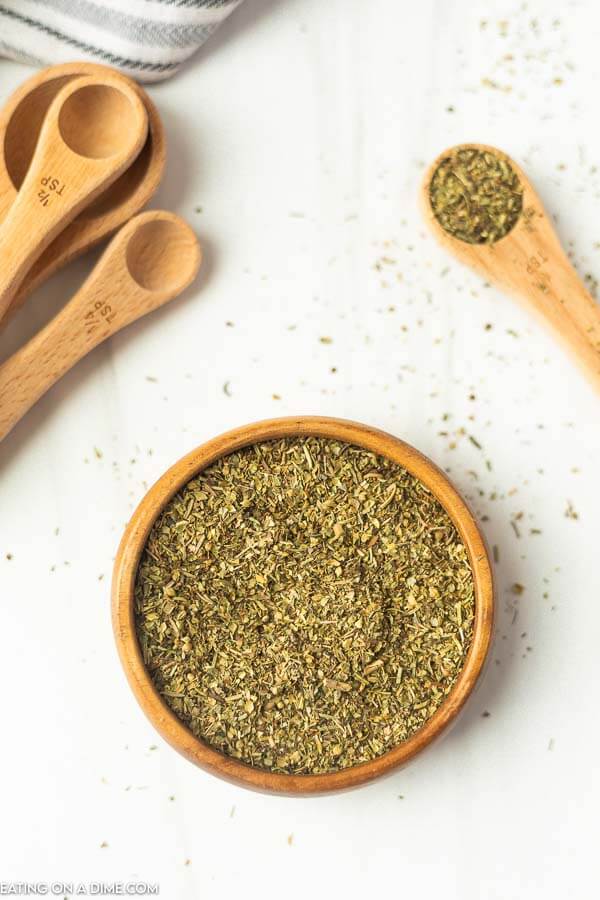 Close up image of Italian Seasoning in a bowl with teaspoons on the side.