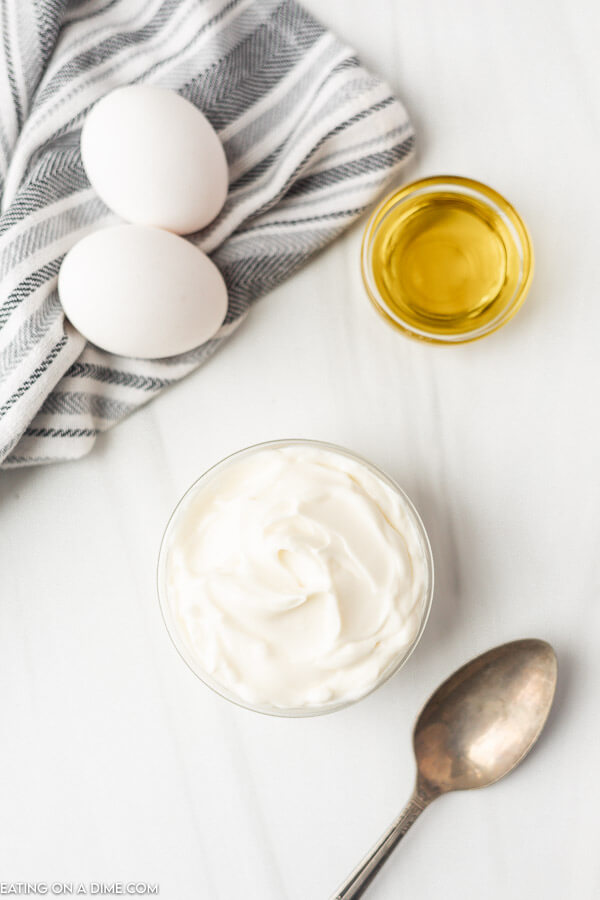 Close up image of Mayonnaise in a bowl with a side of oil and two eggs. 