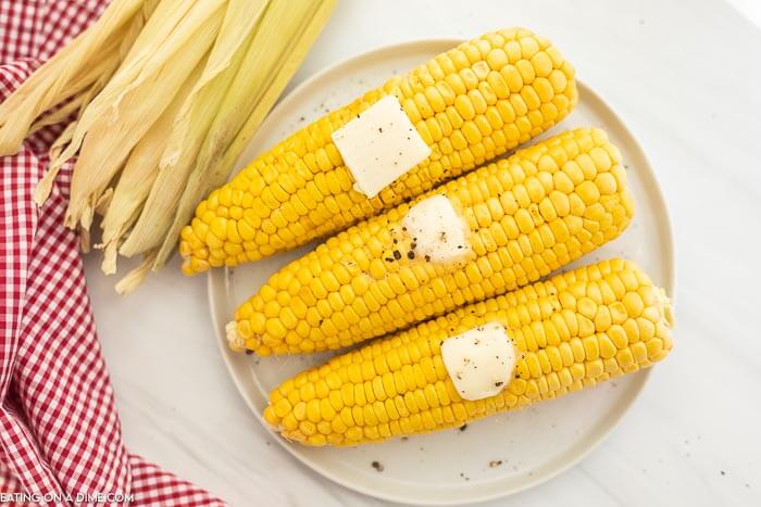Corn on the Cob on a white plate with butter on top. 