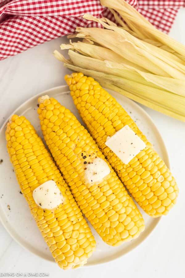 Corn on the Cob on a white plate with butter on top. 