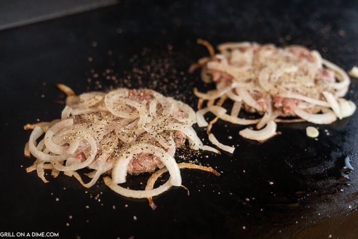 Onions on burgers being grilled. 