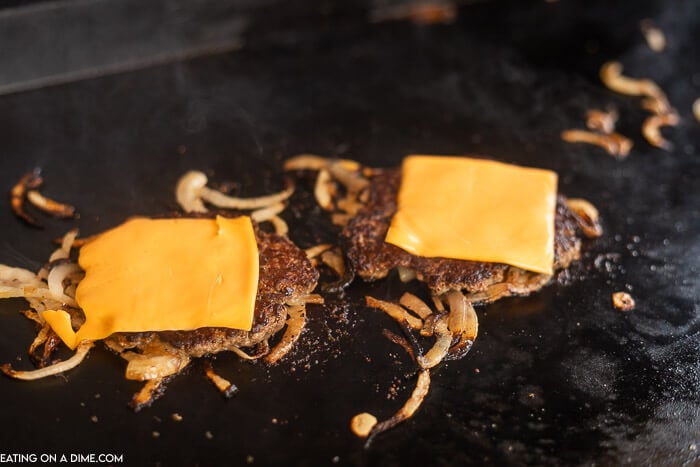 Cheese topped burgers on grill. 