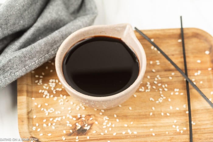 A white bowl of soy sauce on a cutting board