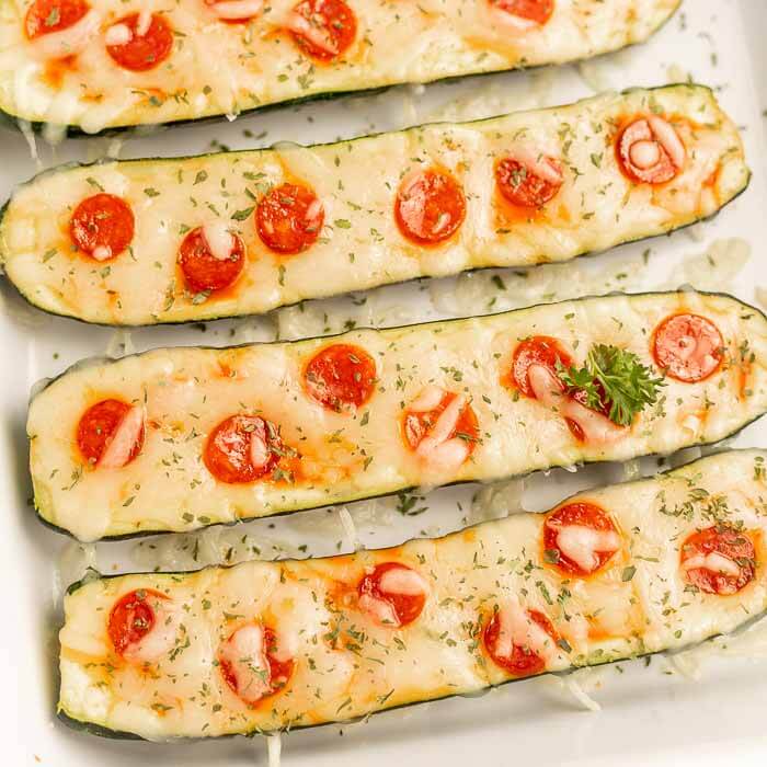 Close up image of zucchini pizza boats in a baking dish.