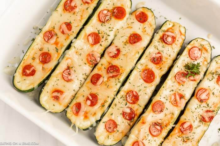 Close up image of zucchini pizza boats in a baking dish.