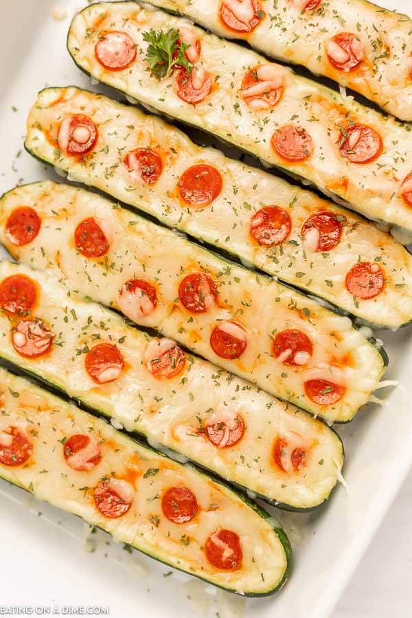 Close up image of zucchini pizza boats in a baking dish. 