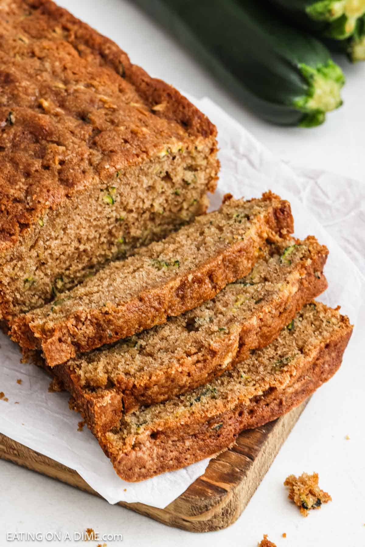 Sliced baked bread on a wooden platter with parchment paper.
