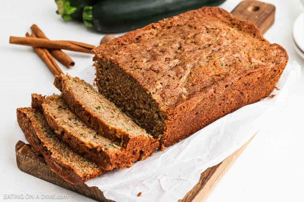 Sliced zucchini bread on a wooden platter with parchment paper.