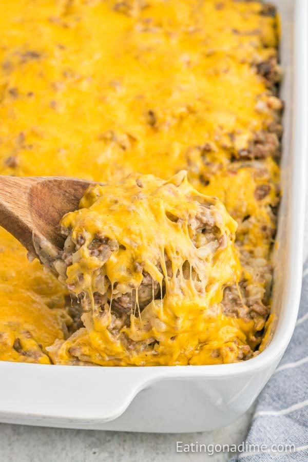 Close up image of hamburger casserole in a baking dish with a wooden spoon.