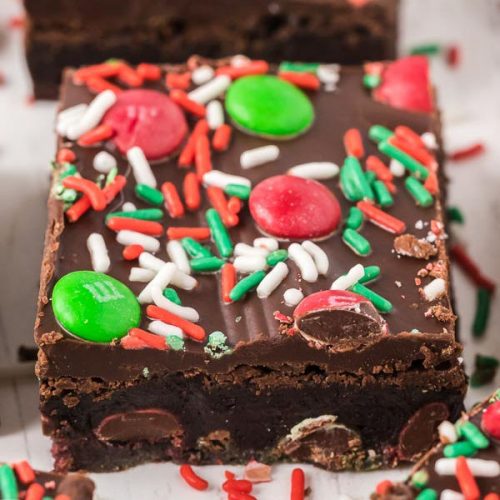 A rich, fudgy Christmas Brownie topped with red and green candies and festive red, green, and white sprinkles. This holiday treat is decorated to bring a cheerful touch to your celebrations.