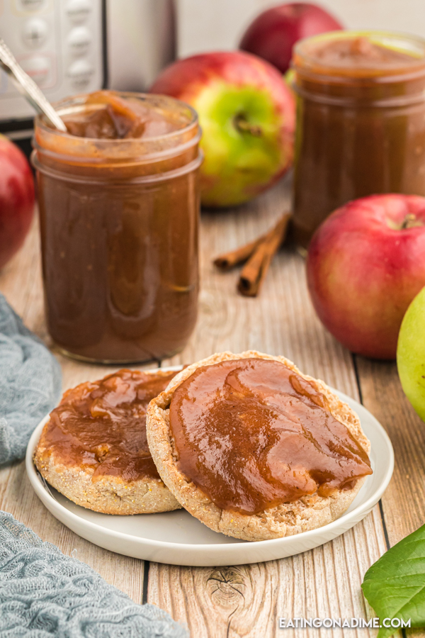 Apple Butter in a jar behind a plate of English Muffins. 