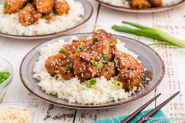 Close up image of sesame chicken on rice on a plate