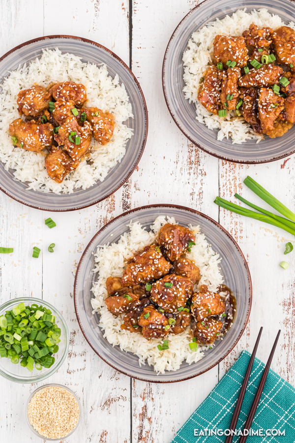 Close up image of sesame chicken on rice on a plate