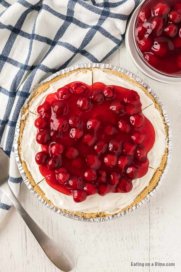 A close up image of whole cheesecake with cherries on top. 