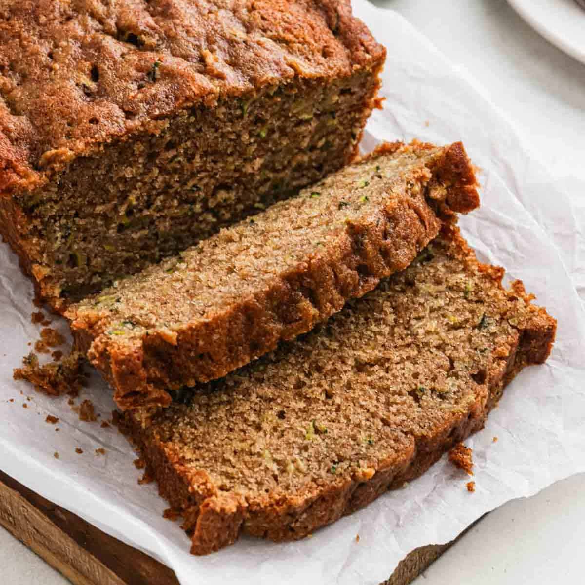 Sliced zucchini bread on a wooden platter lined with parchment paper.