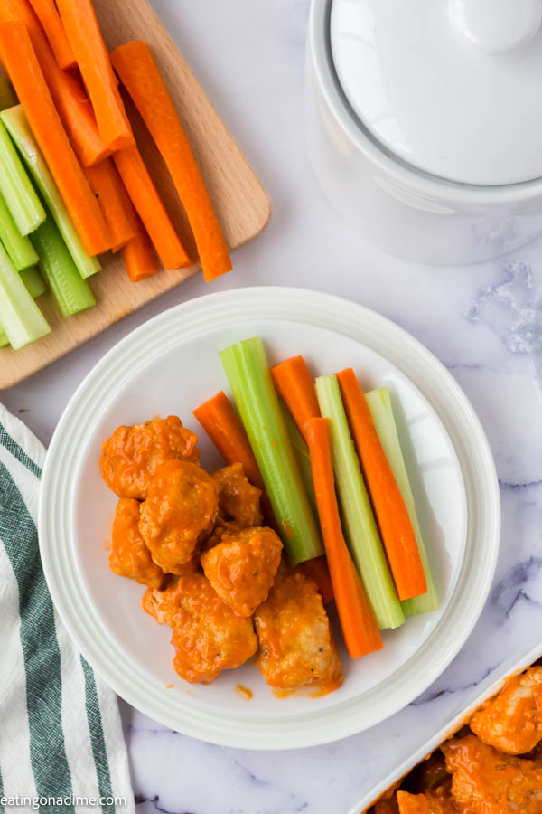 Boneless Chicken Wings  in a bowl beside celery and carrot sticks. 