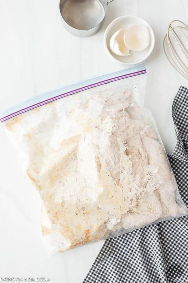 ziplock bag with flour and seasoning being mixed with chicken tenders