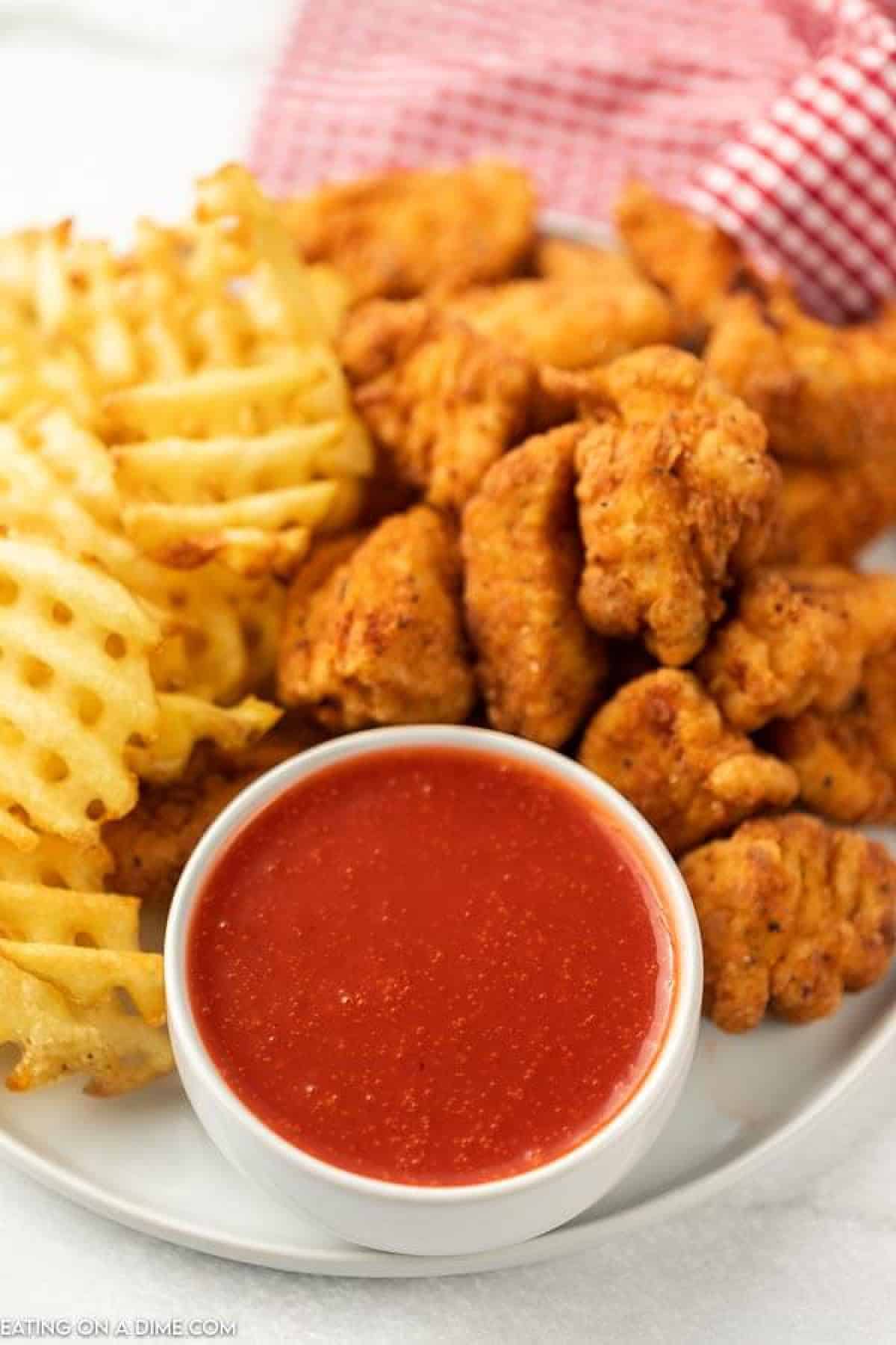 Close up image of polynesian sauce with a side of fries and chicken nuggets