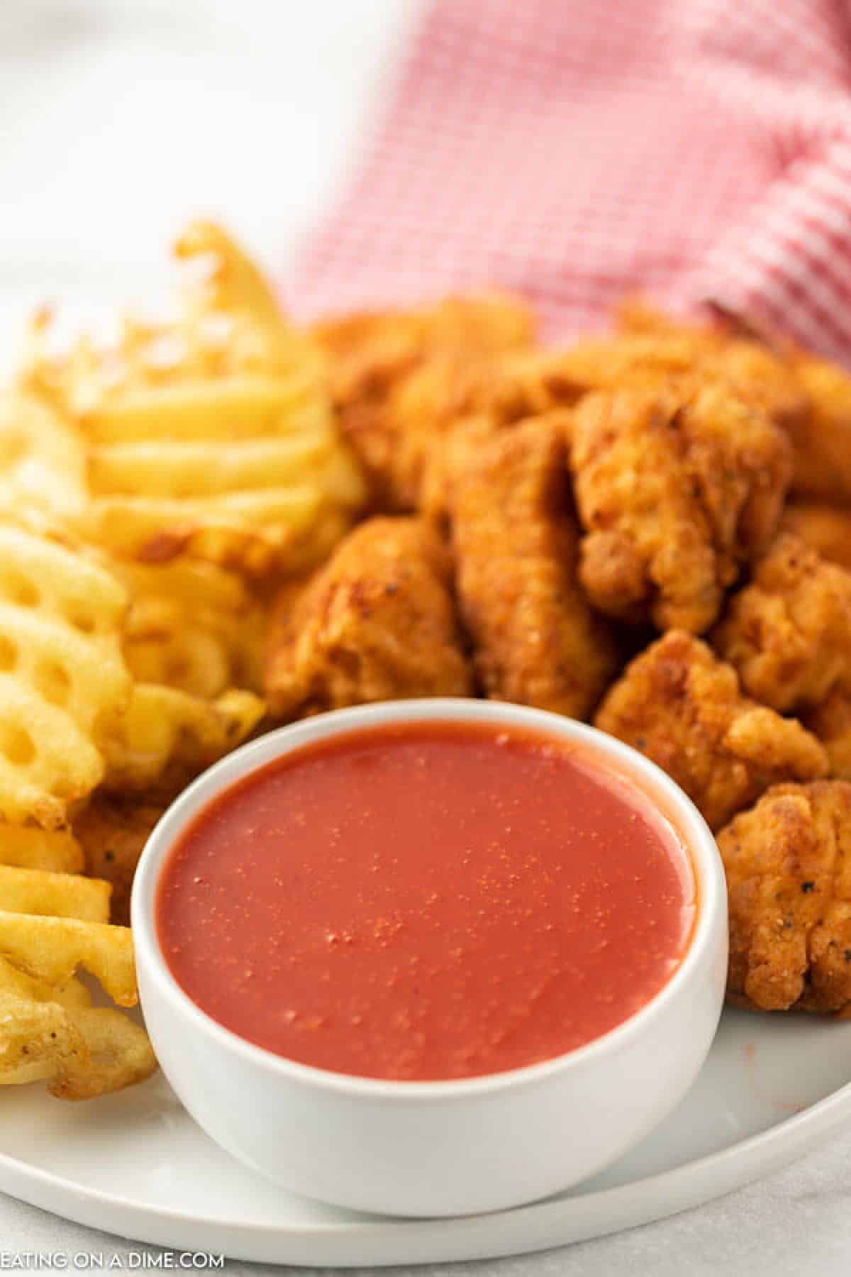 Close up image of polynesian sauce with a side of fries and chicken nuggets