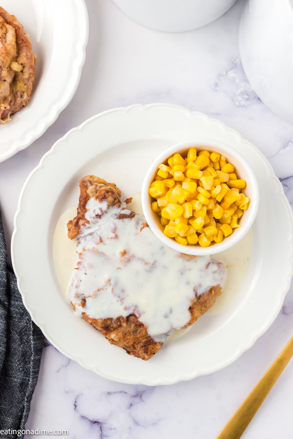 Chicken Fried steak on a white plate with a side of corn