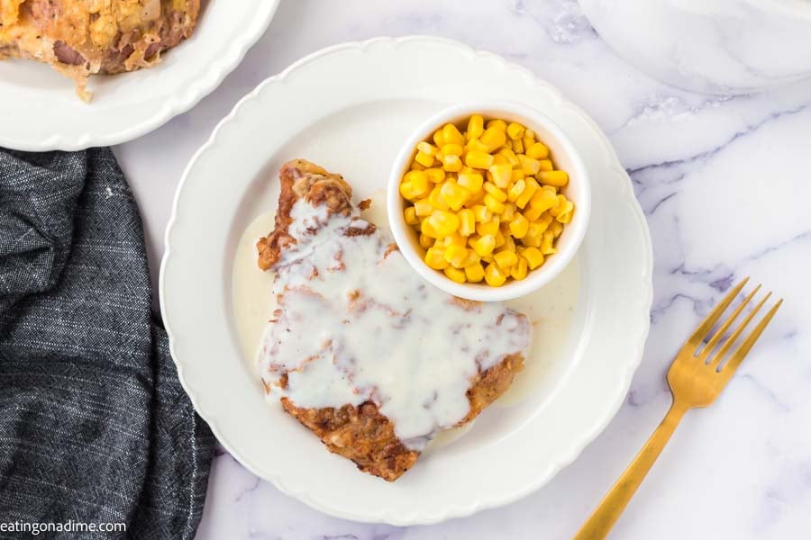 Chicken Fried steak on a white plate with a side of corn