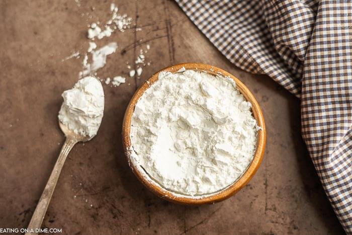 A brown bowl of cornstarch with a serving on a spoon.