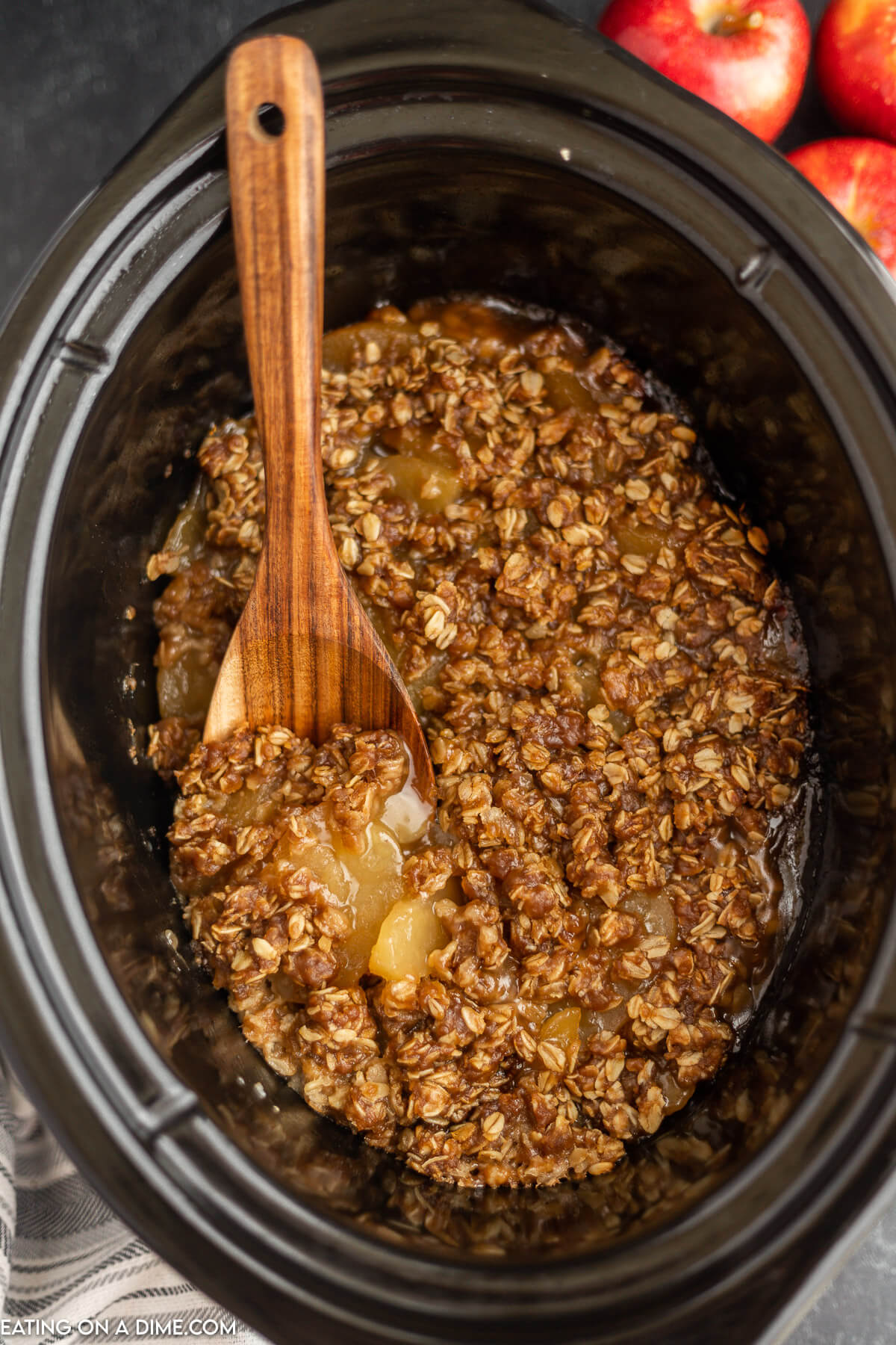 Apple Crisp in the Crock Pot with a wooden spoon