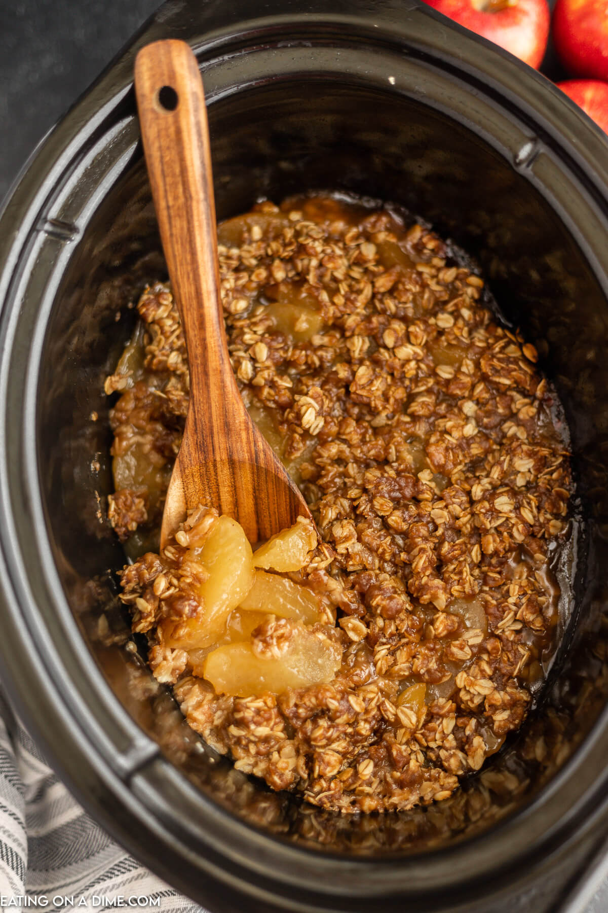 Apple Crisp in the Crock Pot with a wooden spoon