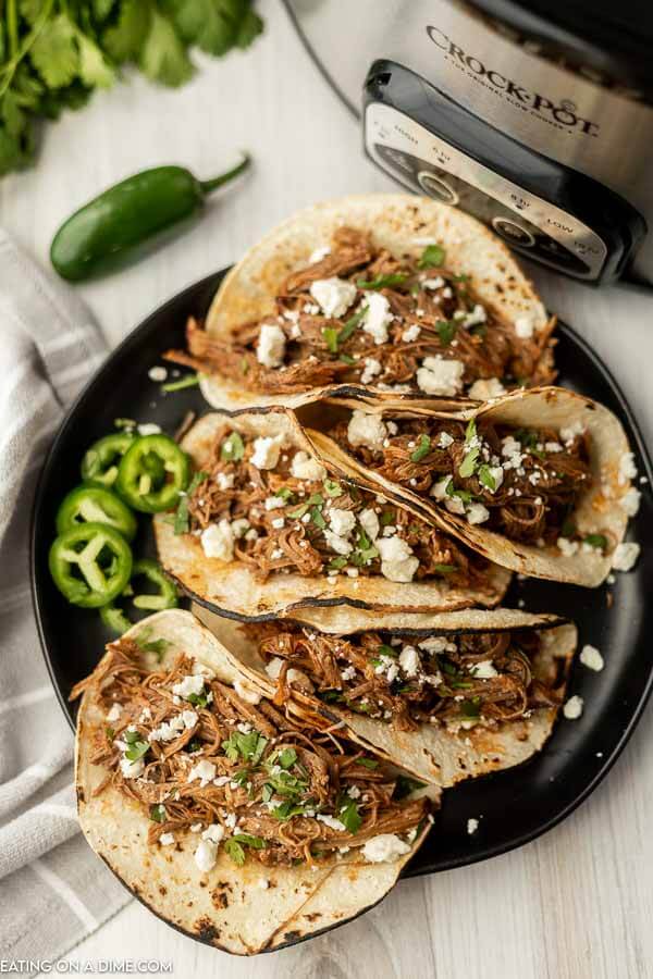 Close up image of shredded beef tacos on a plate.