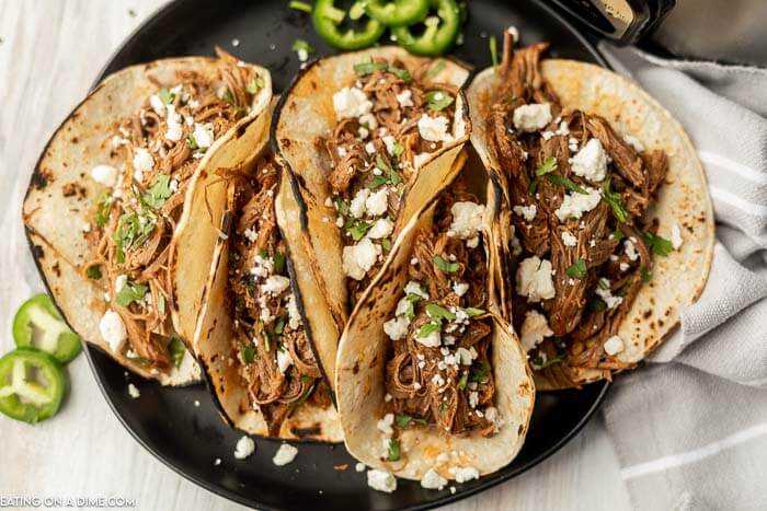 Close up image of shredded beef tacos on a plate.