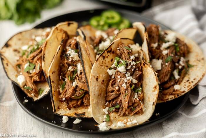 Close up image of shredded beef tacos on a plate.