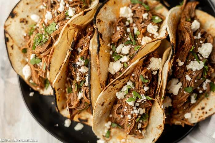 Close up image of shredded beef tacos on a plate.