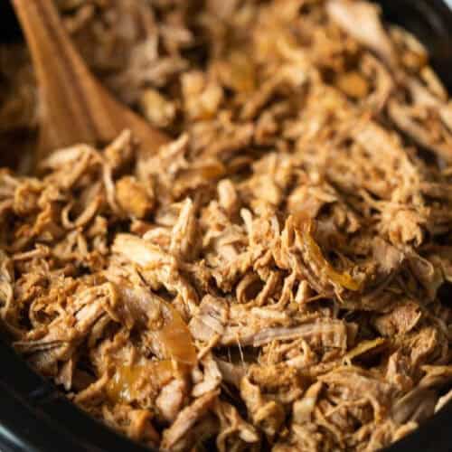 Close-up of shredded, seasoned meat being stirred to go with the best pork sides.