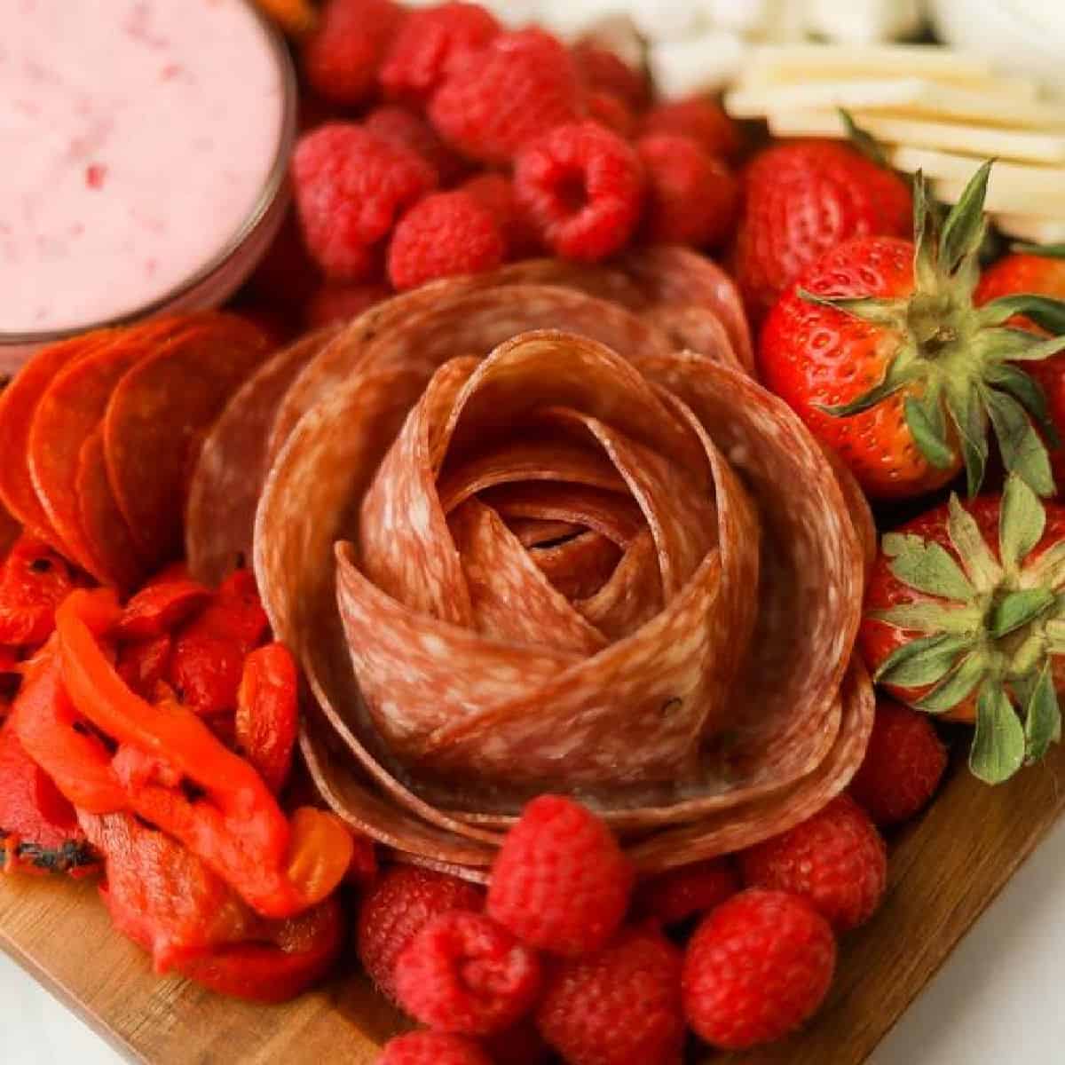 Salami rose on a platter with a side of raspberries.