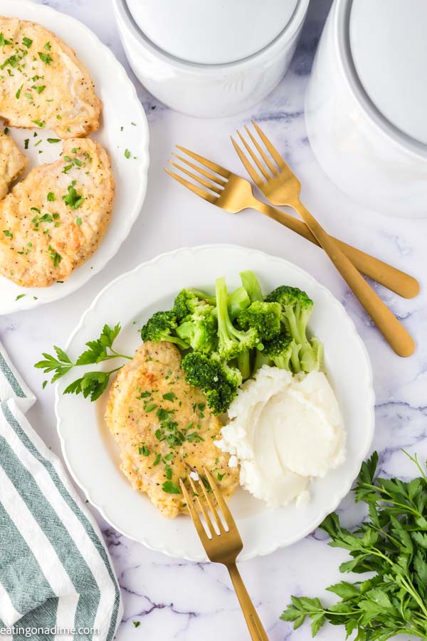 Close up image of fried pork chops on a plate with a side of steamed broccoli and mashed potatoes