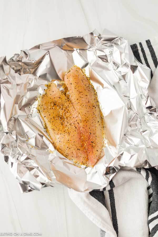 Uncooked Tilapia in a foil with seasoning on top