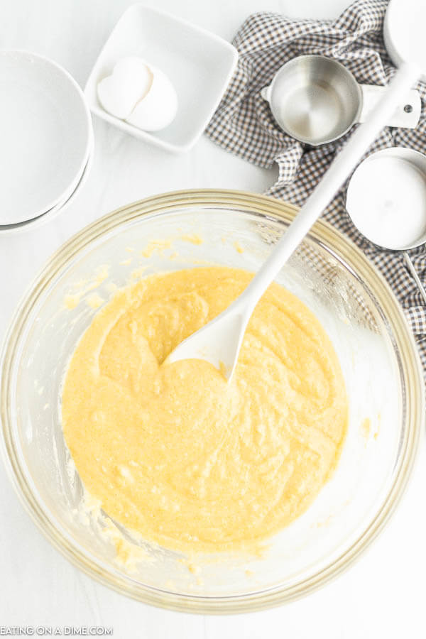 Cornbread batter being mixed in a bowl with a spoon