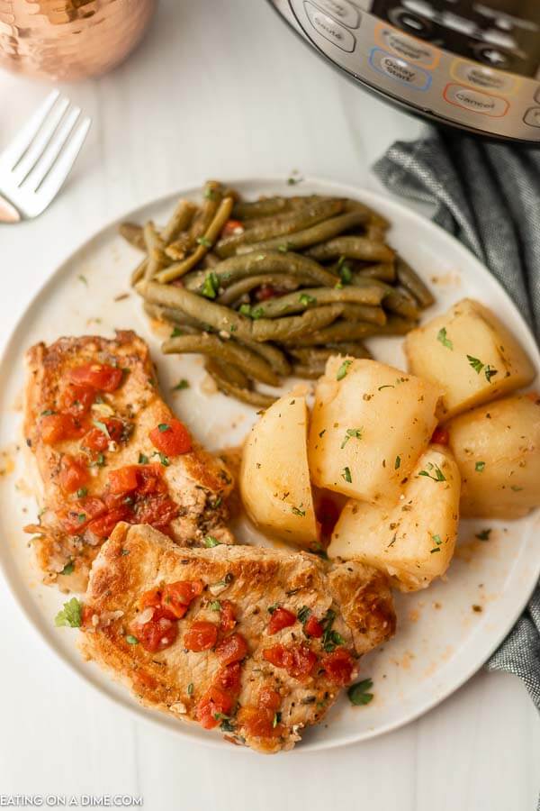 Italian Pork Chops with a side of roasted potatoes and green beans on a plate