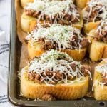 Slices of toasted bread topped with seasoned ground beef and shredded cheese, arranged on a baking sheet