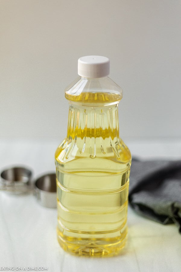 A bottle of oil with two measuring cups